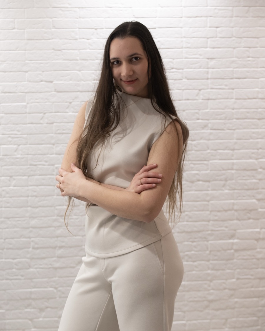 Heidi Sanchez Pau with arms crossed, standing against a white brick wall
